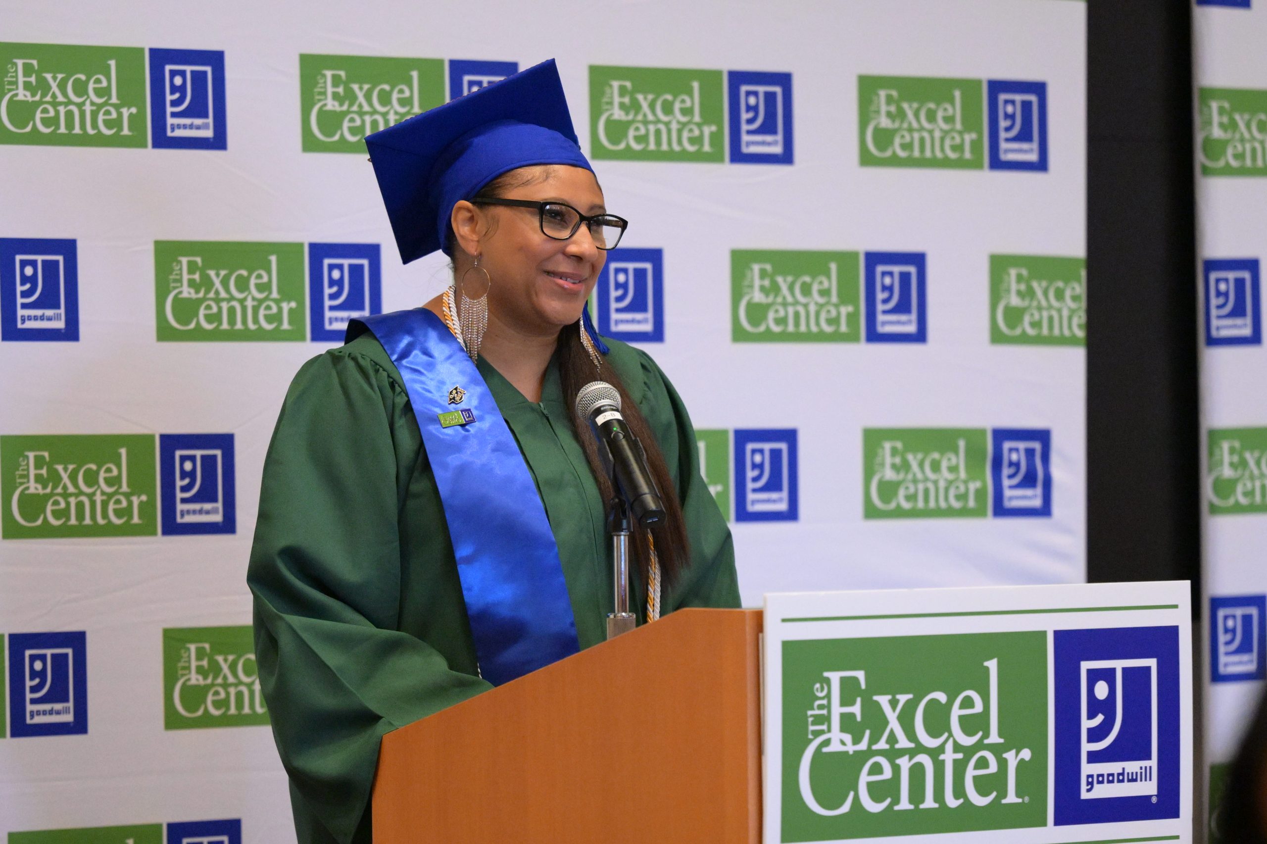 Student smiling in cap and gown at podium