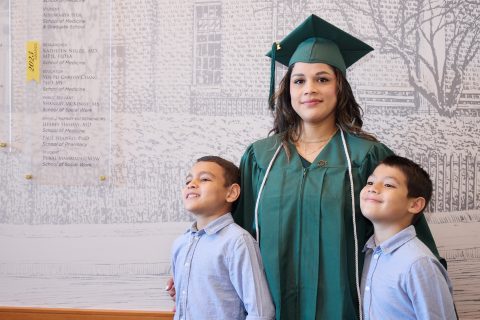 A graduate of Goodwill's Excel Center, a high school for adults 21+, poses in her graduation gown with her two young sons.