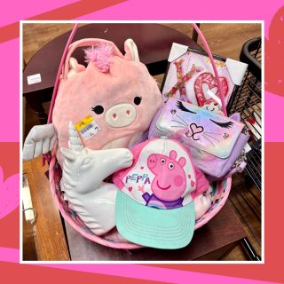 A Galentine's gift basket full of thrifted items for a little girl including pink room decor, a unicorn Squishmallow, a unicorn lamp, a cat purse, and a Peppa Pig hat.