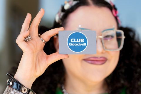 Shopper holding club goodwill loyalty card and smiling